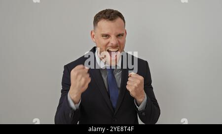 Der aufgeregte Mann in Geschäftskleidung ballt Fäuste vor weißem Hintergrund und strahlt Erfolg und Begeisterung im Unternehmensumfeld aus. Stockfoto