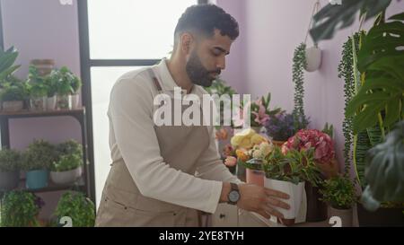 Ein junger hispanischer Mann mit Bart arrangiert Blumen drinnen in einem bunten Blumenladen. Stockfoto