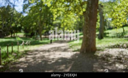 Verschwommener Blick auf die Menschen, die in den sonnendurchfluteten Gärten der Villa borghese in rom spazieren, mit grünem Laub und schimmerndem Licht. Stockfoto