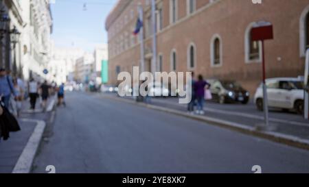 Verschwommener Blick auf die Straße in rom, auf der Menschen entlang einer alten Stadtstraße mit historischen Gebäuden spazieren gehen und eine defokussierte urbane Atmosphäre in italien einfangen. Stockfoto