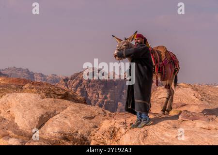 Der jordanische Beduin bei dem Esel an der Klippe von Petra, einem historischen Ort in Jordanien. Stockfoto