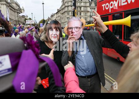 London, UK, 30. Oktober 2024. Ein Mann und eine Frau tragen Rachel Reeves und Kier Starmer Masken bei einer WASPI-Frauendemonstration am Parliament Square am Budgettag. Während die Labour-Kanzlerin Rachel Reeves das erste Labour-Budget für 14 Jahre ausgibt, finden Proteste vor den Kammern des Parlaments statt. Die erste Kanzlerin des Vereinigten Königreichs hat wiederholt vor hohen Steuererhöhungen und Ausgabenkürzungen von bis zu 40 Milliarden Pfund gewarnt. WASPI-Demonstrantinnen besetzen den Parlamentsplatz, während das Budget den Abgeordneten und dem Land zur Verfügung gestellt wird. Quelle: James Willoughby/ALAMY Live News Stockfoto