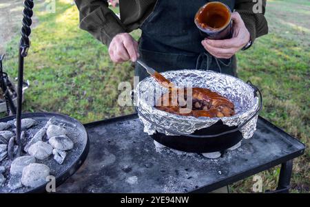 Ein Ring aus Früchten und Panade mit karmel, der in der freien Natur in einem niederländischen Ofen über Holzkohle gekocht wird, zeigt eine Delikatesse bei der Herstellung. Bokeh Stockfoto