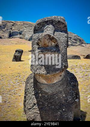 Zwei Moai-Statuen auf der Osterinsel, Chile, vor einer felsigen Landschaft und blauem Himmel. Diese antiken Schnitzereien gehören zum UNESCO-Weltkulturerbe Stockfoto