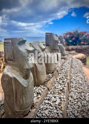 Reihe von Miniatur-Moai-Statuen, die draußen auf der Osterinsel in Chile ausgestellt werden. Diese Replikate erfassen Rapa Nuis antike Kunst vor dem Hintergrund des Himmels Stockfoto