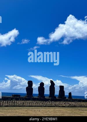 Silhouette der ikonischen Moai-Statuen auf der Osterinsel (Rapa Nui), Chile, vor einem hellblauen Himmel und Ozeanhorizont, die das alte polynesische symbolisieren Stockfoto