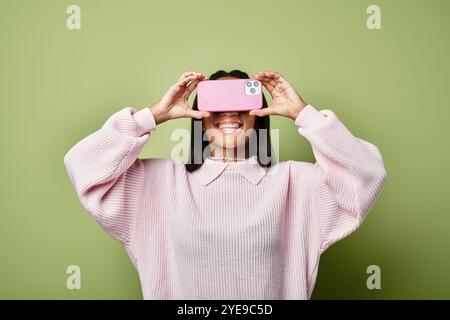 Eine Frau lächelt beim Fotografieren breit und trägt gemütliche Herbstkleidung. Stockfoto