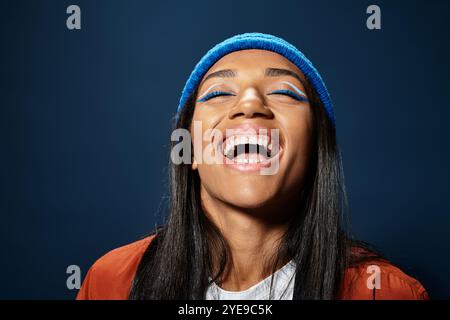 Eine junge Frau strahlt vor Aufregung und zeigt ihr stilvolles Herbstoutfit und ihr leuchtendes Make-up. Stockfoto