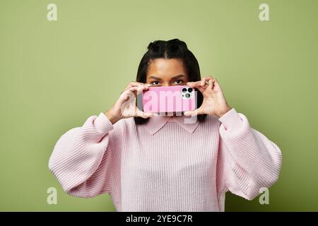 Eine junge Frau in kuscheliger Herbstkleidung macht ein Foto, während sie ihr warmes Ensemble zeigt. Stockfoto