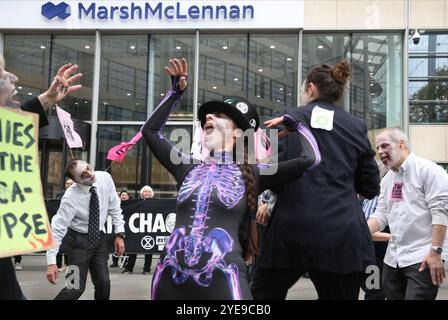 London, England, Großbritannien. 30. Oktober 2024. Während der Demonstration tanzen die als Zombies verkleideten Demonstranten vor Marsh McLennans Büros. Anhänger der Extinction Rebellion (XR) in Zombiekleidung marschieren durch die City of London und halten an und demonstrieren vor den Büros von Versicherungsunternehmen, die trotz der Warnungen vor einer Klimakrise von Wissenschaftlern weiterhin Unternehmen für fossile Brennstoffe versichern. Die Demonstranten glauben, wenn die Versicherungsgesellschaften ihre Beteiligung an diesen Unternehmen beenden würden, würden sie es schwer tun, weiter zu bauen. Die Klage richtete sich speziell an den Versicherer Stockfoto