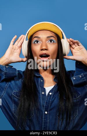 Eine junge Frau trägt ein trendiges Outfit und Kopfhörer, die Freude beim Musikhören zum Ausdruck bringt. Stockfoto