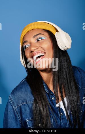 Die junge Frau strahlt Freude aus, während sie Musik in herbstlichen Schichten und leuchtenden Farben umarmt. Stockfoto