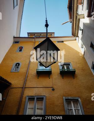 Die Laterne hängt im Innenhof der Altstadt. Straßenlaterne in der Altstadt. Blick auf die Straßenlaterne, senfgelbe Fassade im Hintergrund. Stockfoto