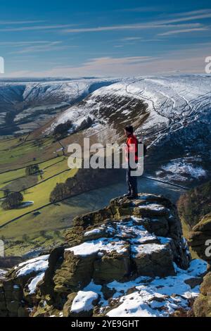 Walker blickt über das Edale Valley von der Felsformation Ringing Roger im Winter, Kinder Scout, Peak District National Park, Derbyshire, England, Großbritannien Stockfoto