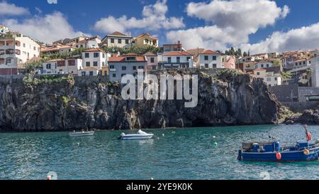 Unterkunft entlang der Klippen und Boote entlang der Küste in der Stadt Camera de Lobos auf der Insel Madeira, Portugal Stockfoto