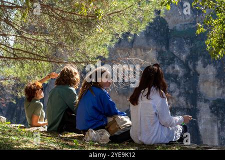 Jugendliche Momente: Freunde entspannen im Schatten, eingerahmt von Baumzweigen und Nature's View Stockfoto