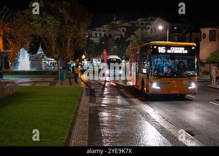 Stadtbusse auf der Straße bei Nacht in der Küstenstadt Funchal auf der Insel Madeira, Portugal; Funchal, Madeira, Portugal Stockfoto