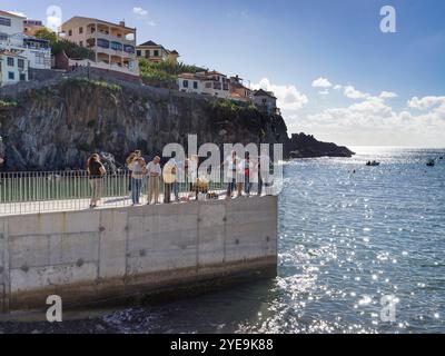 Einheimische fischen und genießen den Hafenblick von einem Pier in der Küstenstadt Camara de Lobos auf Madeira, Portugal Stockfoto