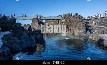 Touristen, die von einem erhöhten Fußweg entlang der Küste von Porto Moniz auf der Insel Madeira, Portugal; Porto Moniz, Madeira, Portugal Stockfoto