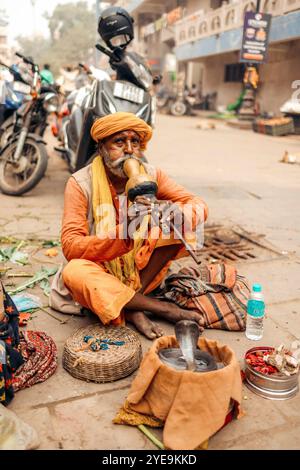 Schlangenbeschwörer sitzt auf der Straße in Varanasi, Indien; Varanasi, Uttar Pradesh, Indien Stockfoto