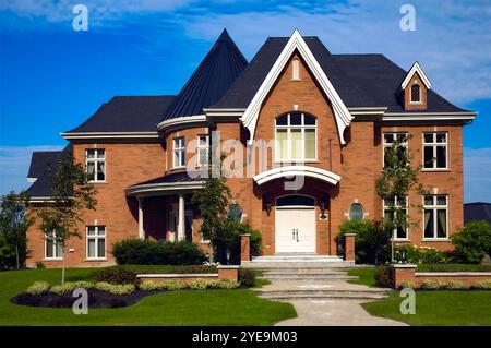 Wohnhaus mit Gehweg, Stufen und landschaftlich gestaltetem Hof unter blauem Himmel und Wolken; Quebec, Kanada Stockfoto