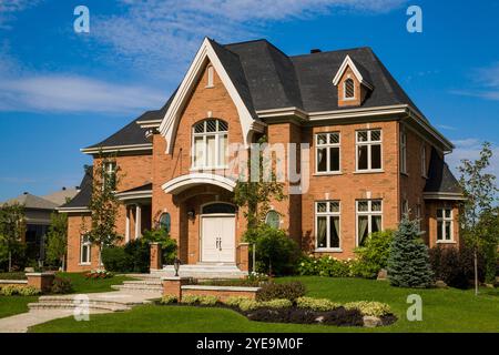 Wohnhaus mit Gehweg, Stufen und landschaftlich gestaltetem Hof unter blauem Himmel und Wolken; Quebec, Kanada Stockfoto