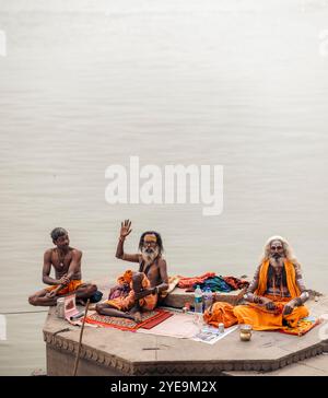 Drei hinduistische Männer sitzen am Ganges in Varanasi, Indien; Varanasi, Uttar Pradesh, Indien Stockfoto