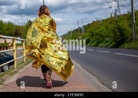 Frau, die nach dem Sportrennen mit Thermaldecke läuft Stockfoto