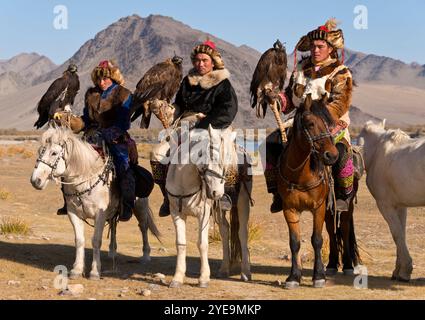 Mongolische Adlerjäger zu Pferd mit Goldenen Adlern (Aquila chrysaetos) beim Adlerfest in der Mongolei; Olgii, Mongolei Stockfoto