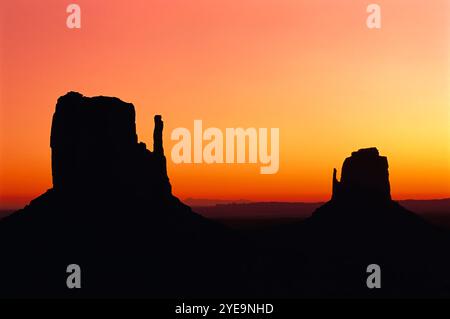 Monument Valley mit einem leuchtenden Himmel bei Sonnenuntergang und Silhouette von zwei Buttes (West Mitten Butte und East Mitten Butte), Arizona, USA Stockfoto