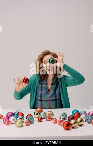 Eine fröhliche junge Frau organisiert lebendige Ornamente, während sie sich auf die Weihnachtszeit vorbereitet. Stockfoto