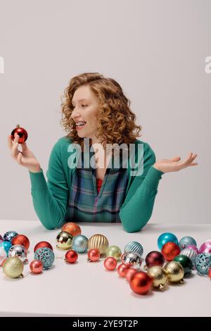 Eine junge Frau mit lockigen Haaren lächelt, umgeben von festlichen Dekorationen. Stockfoto