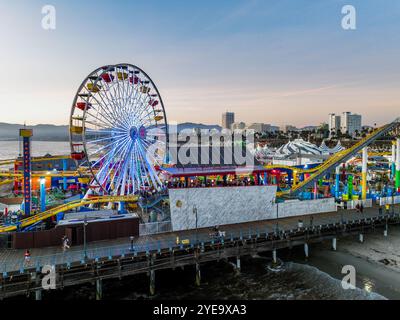 Der Santa Monica Beach Pier in Kalifornien, mit Pacific Park at Sunset von einer UAV-Drohne mit Blick auf die Lichter der Stadt Stockfoto