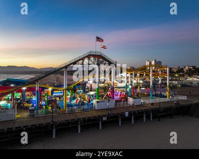 Der Santa Monica Beach Pier in Kalifornien, mit Pacific Park at Sunset von einer UAV-Drohne mit Blick auf die Lichter der Stadt Stockfoto