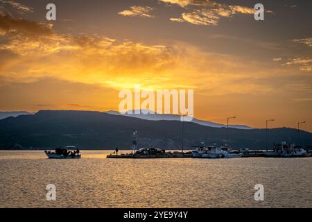 Ein kleines Fischerboot, das den Hafen verlässt und am Morgen mit einem wunderschönen goldenen Sonnenaufgang aufs Meer fährt. Stockfoto