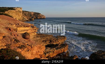 Surfer im Nordatlantik warten auf eine Welle von einem wunderschönen Strand Praia do Zavial mit zerklüfteten Klippen in Sagres, der an der ... Stockfoto