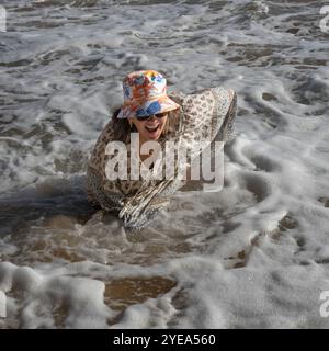 Frau genießt Zeit im Meer Schaum des Ozeans Surfen an einem der Strände von Sagres an der portugiesischen Küste; Sagres, Faro, Portugal Stockfoto