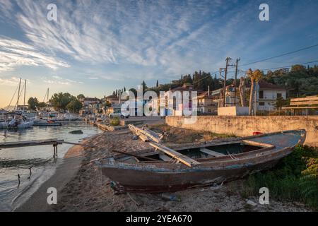 Lefkada, Griechenland- 10.18.2024. Ein altes kleines Holzboot am Hafenstrand von Lygia im Morgenlicht mit wunderschönen Wolken. Stockfoto