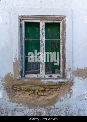 Nahaufnahme eines verwitterten und verkleideten hölzernen Fensterrahmens und einer Wand mit abblätternder Farbe; Lagos, Faro, Portugal Stockfoto