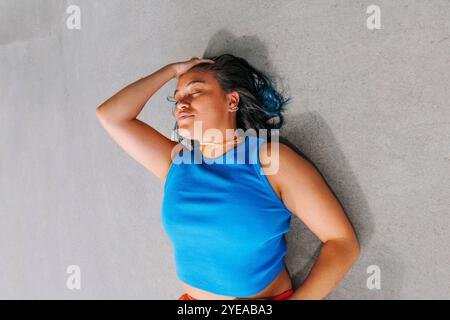 Hochwinkelansicht einer jungen Frau mit Hand im Haar auf dem Boden liegend Stockfoto