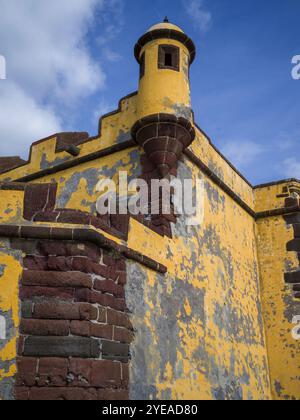 Architektonisches Detail eines verwitterten Wachturms und einer Steinmauer am Ufer des Fort Sao Tiago in der Küstenstadt Funchal auf der Insel M... Stockfoto