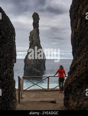 Frau steht an einem Geländer am Wahrzeichen des Schiffstapels Ilheus da Ribeira da Janela auf Madeira, Portugal Stockfoto