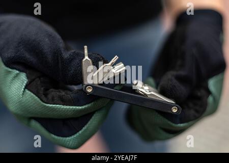 Nahaufnahme einer Hand mit Handschuhen, die ein Fahrrad-Multiwerkzeug hält Stockfoto