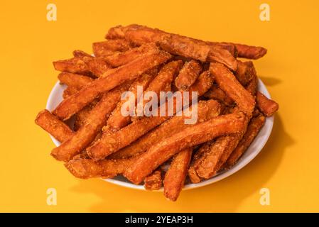 Hausgemachte Orange Süßkartoffel Pommes mit Salz und Pfeffer isoliert auf gelbem Hintergrund Stockfoto