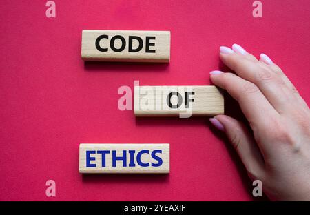 Symbol für Ethikkodex. Konzeptworte Ethik-Kodex auf Holzblöcken. Schöner roter Hintergrund. Geschäftsmann Hand. Business und Ethik-Konzept. Stockfoto