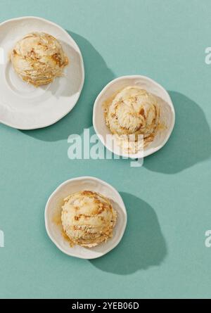 Teller mit Karamell-Eiskugeln auf blauem Hintergrund, Draufsicht Stockfoto