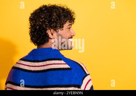 Foto-Porträt des gutaussehenden jungen Mannes Rückansicht Blick leerer Raum gekleidet stilvolles blau gestreiftes Kleid isoliert auf gelbem Farbhintergrund Stockfoto