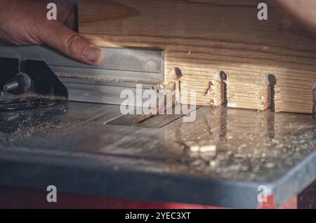 Große Holzplatte mit Rundlöchern in der Tischlerei. Kreissäge. Zimmermannshand. Ausschneiden Stockfoto