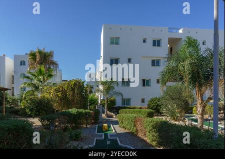 Ein ruhiger Garten mit üppigem Grün und Pfaden, eingebettet zwischen hellen weißen Wohnhäusern. Stockfoto