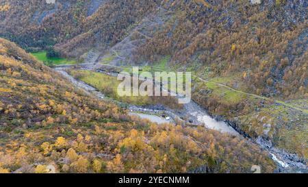 Aus der Vogelperspektive auf einen sich windenden Fluss, der durch ein üppiges Tal fließt, umgeben von herbstfarbenen Bäumen und felsigen Hügeln. Stockfoto